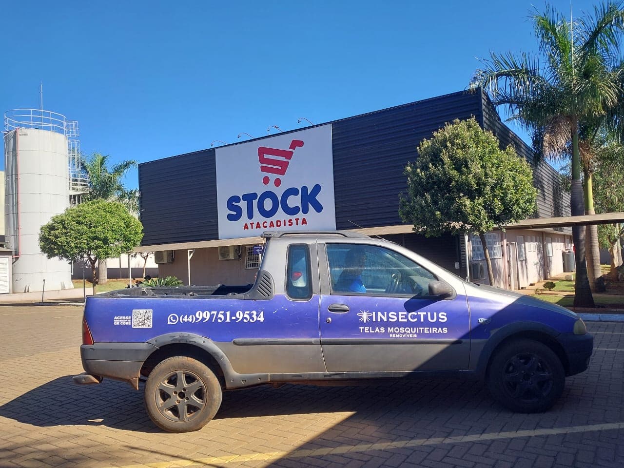 Veículo da Insectus com a marca e o telefone estacionado em frente à loja Stock Atacadista durante o atendimento
